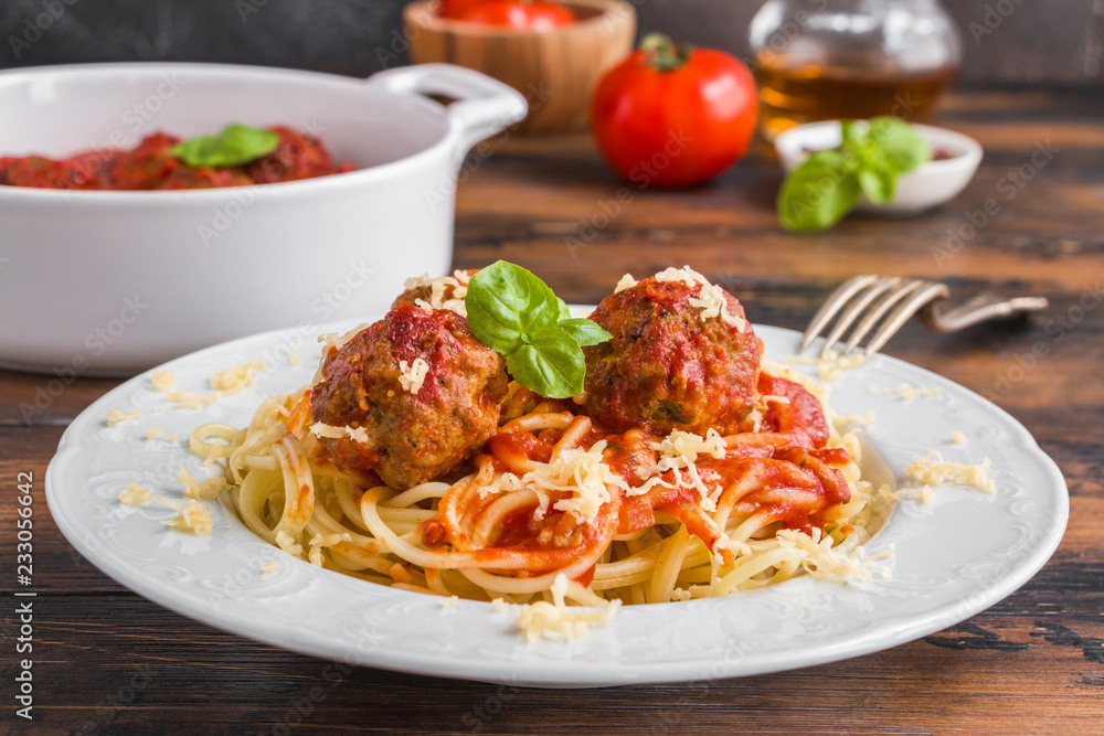 Pasta and meatballs with tomato sauce, white casserole and plate on wooden rustic table