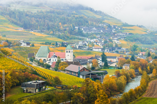 Picturesque autumnal view on Novacella, Varna, Bolzano in South Tyrol. Mountain scenery in Northern Italy. View from the top on the mountain valley. Colourful vineyards and yellow foliage on trees.