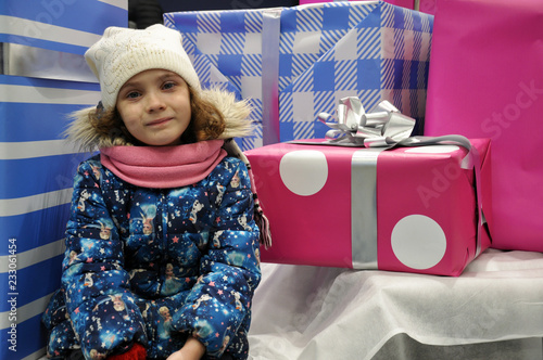 girl in a hat and jacket surrounded by boxes of gifts photo