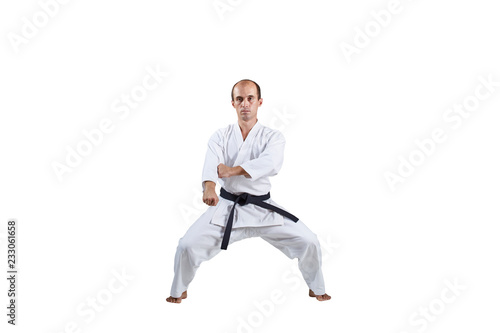 On white background, adult active athlete performs formal karate exercises.