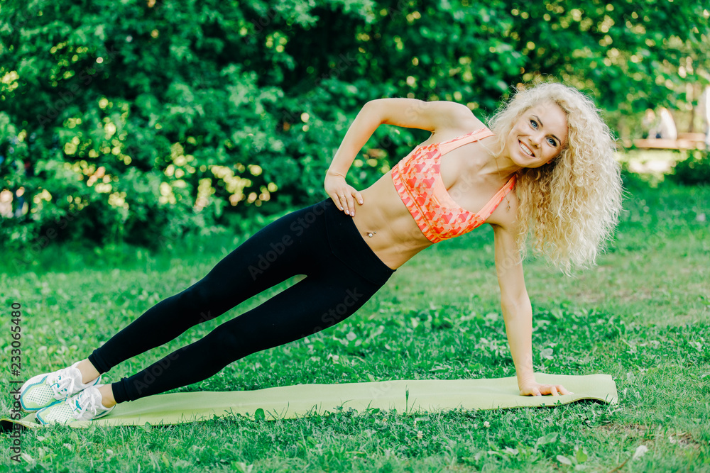 Fototapeta premium Image of young curly-haired sports woman practicing yoga on rug 