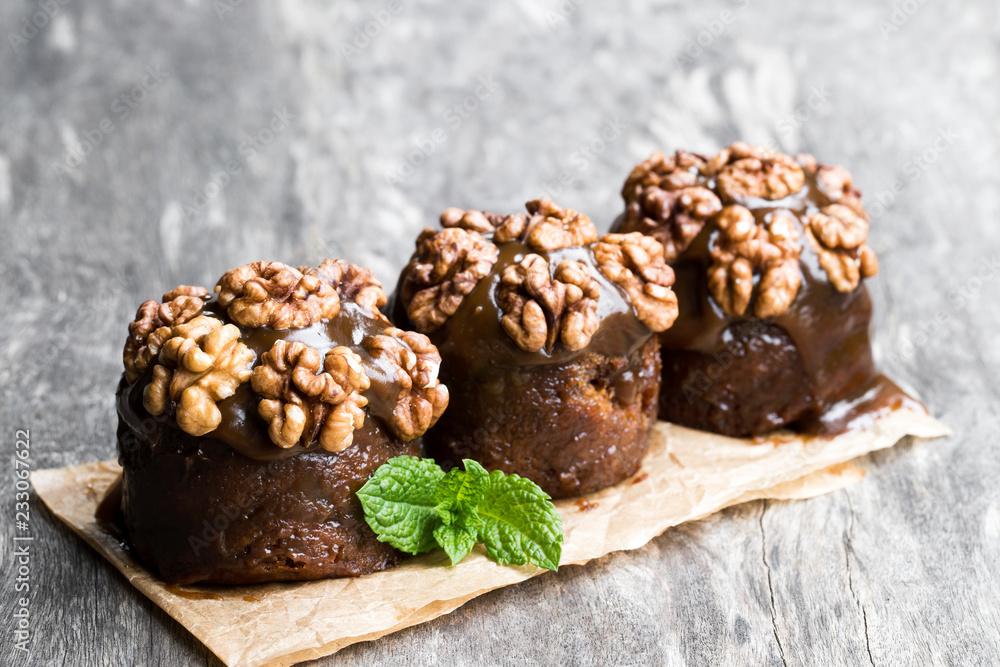 Sticky chocolate and walnut puddings on wooden table Sticky chocolate and walnut puddings on wooden table