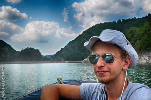 Tourist wearing a hat sitting in the pontoon, sailing on Zaovine Lake in Serbia