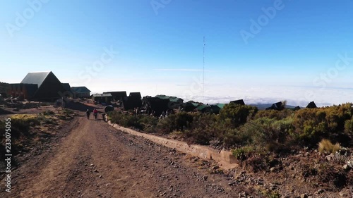 Static shot of a group of people hiking to a small town, on mount Kilimanjaro, on a sunny day, at Horombo hut, in Tanzania, Africa photo