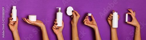 Female hands holding white cosmetics bottles - lotion, cream, serum on violet background. Banner. Skin care, pure beauty, body treatment concept
