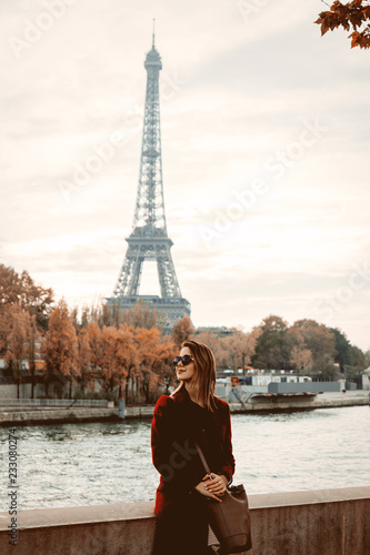 Style redhead girl in red coat and bag at parisian street with view at Eiffel tower in autumn season time © Masson