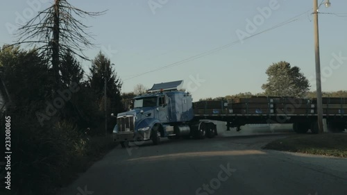 Peterbilt semi truck pulling out of yard and driving down the street front view in slow motion photo