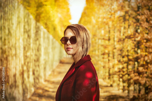Style girl in sunglasses and red coat in Versailles park, France