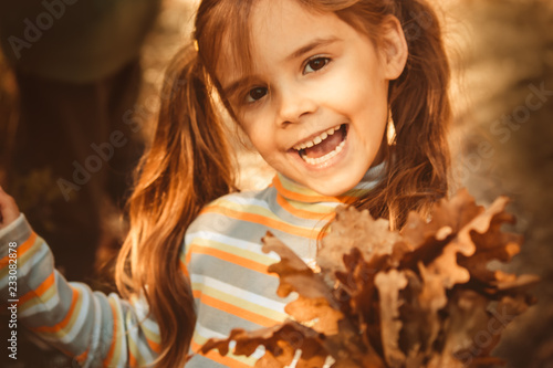 Happy little girl in the fairy autumn forest ,collecting the gold plates Portrait of attractive young girl outdoors