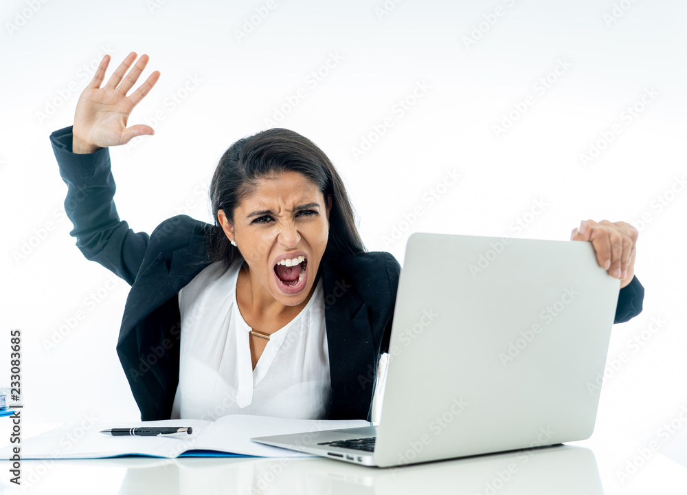 Young beautiful businesswoman shouting at her computer feeling mad and desperate Young beautiful businesswoman shouting at her computer feeling mad and desperate