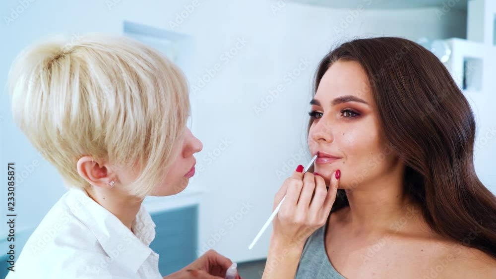 closeup of female makeup artist doing professional makeup for young beautiful woman at beauty salon. people, cosmetics, care, lifestyle, style concept closeup of female makeup artist doing professional makeup for young beautiful woman at beauty salon. people, cosmetics, care, lifestyle, style concept
