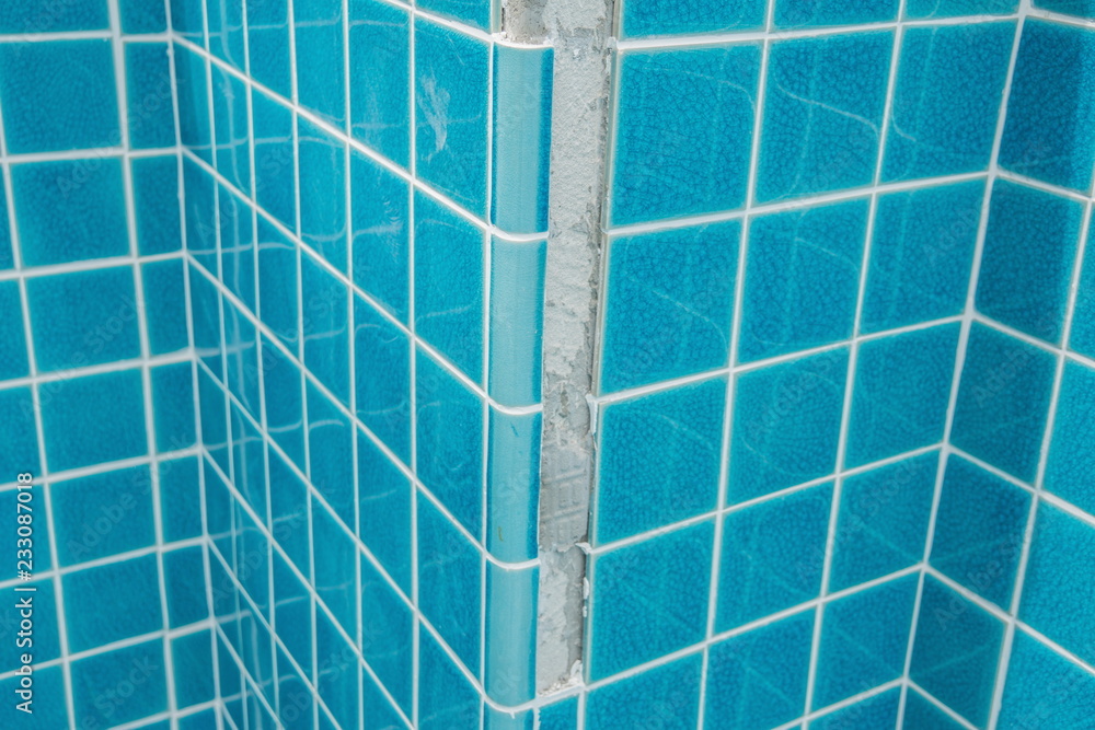 Tiled pool. The man hand while using spacer for installing tiles. 