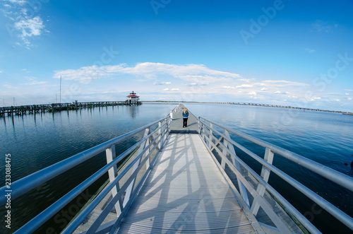 Young adult woman walks out onto a pier near the Choptank River Lighthouse in Cambridge Maryland on a sunny spring day photo