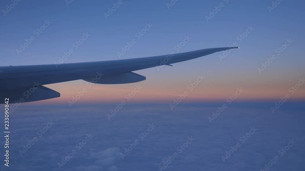 Passenger view from commercial jet. Dawn light over clouds with wing. Light purple and orange colours. Passenger view from commercial jet. Dawn light over clouds with wing. Light purple and orange colours.
