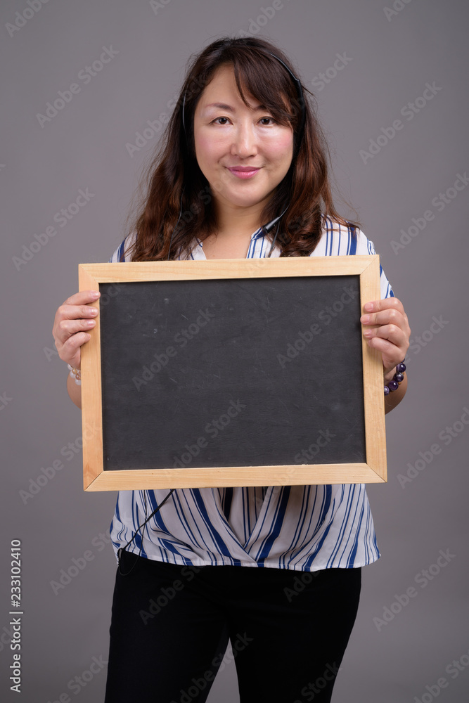 Mature Asian businesswoman holding blackboard with copy space Mature Asian businesswoman holding blackboard with copy space