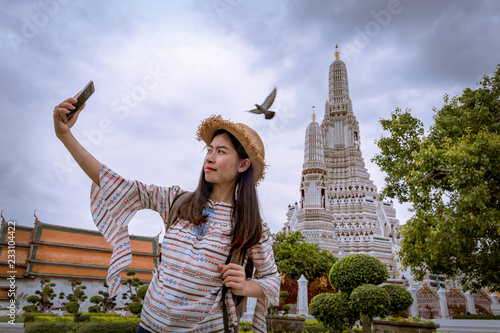 Beautiful Asian woman selfie with smartphone at wat Arun temple on vacation © Small fish