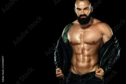 Men fashion concept. Close-up portrait of a brutal bearded man topless in a leather jacket. Athlete bodybuilder on black background.