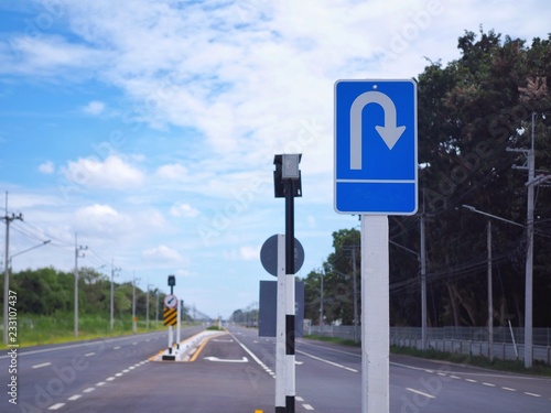 U-turn​ Traffic warning​ sign​ for​ show that the road ahead has a reverse to the car​ and​ blue​ sky​ with​ white​ clouds.