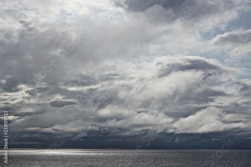 The sun pierces through gathering storm clouds over the Gulf of Alaska.