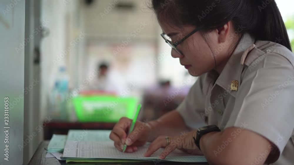 Thai teacher in official uniform working at student examination room Thai teacher in official uniform working at student examination room