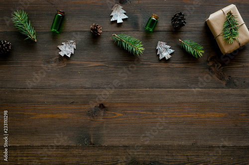 Background with New Year gift. Box wrapped in craft paper, decorated with pine sprig and cones on dark wooden background top view copy space