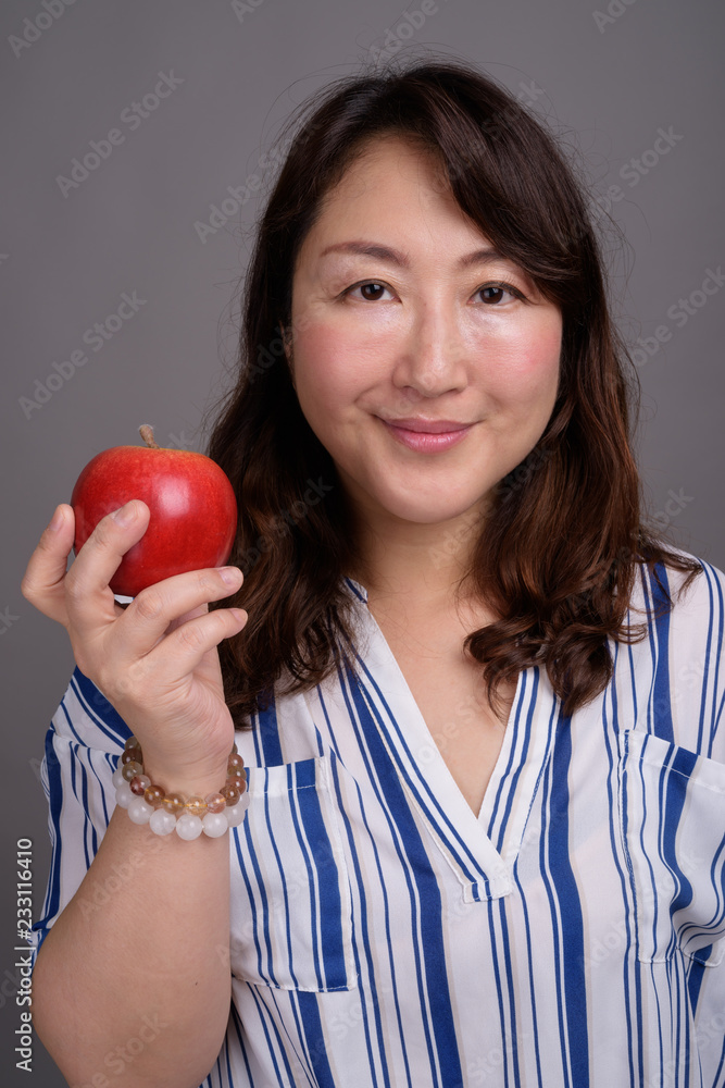 Mature beautiful Asian businesswoman holding healthy apple Mature beautiful Asian businesswoman holding healthy apple