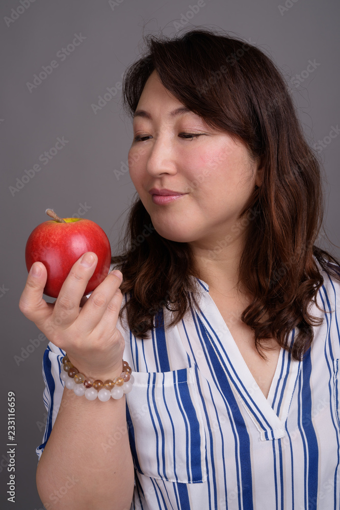 Mature beautiful Asian businesswoman holding healthy apple Mature beautiful Asian businesswoman holding healthy apple