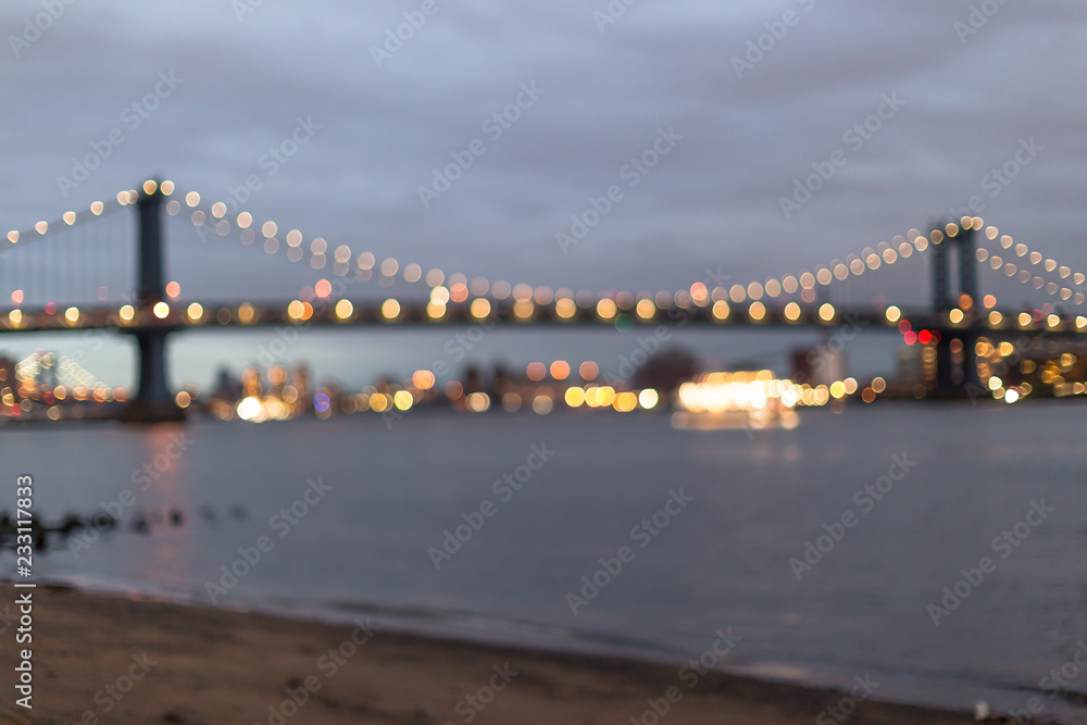 Fototapeta premium Blurred view on Manhattan bridge from the sand beach at sunset