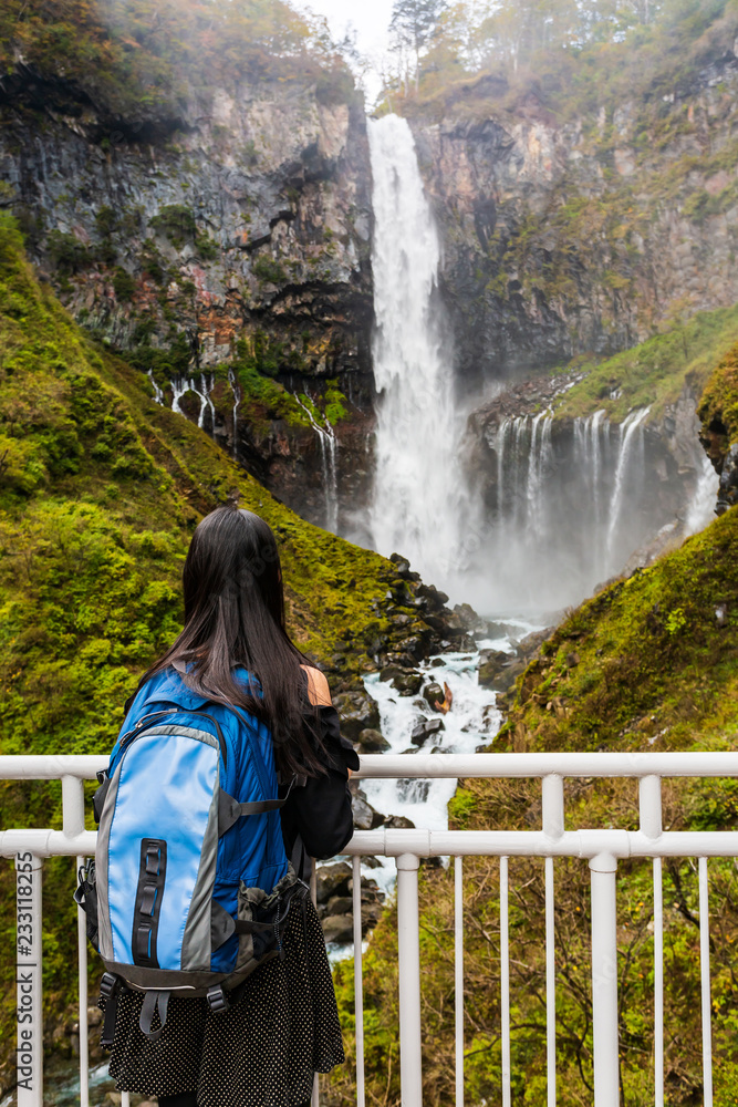 Fototapeta premium Young woman standing look at and enjoying view of nature at Kegon Falls in autumn at the Nikko National Park, Japan.