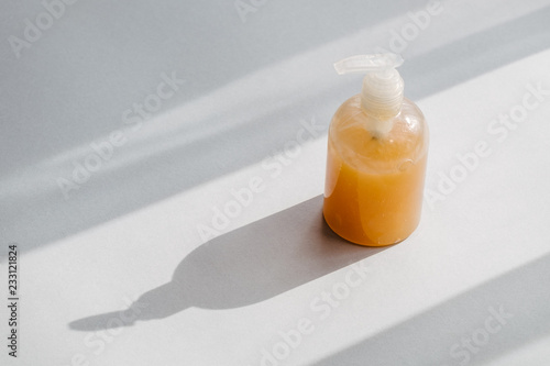 Clear plastic bottle with organic cosmetic product from above. Direct light and shadows. Beauty blogging minimalism concept