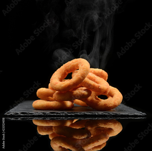 Hot calamari or onion rings on black stone plate and steam smoke on black 