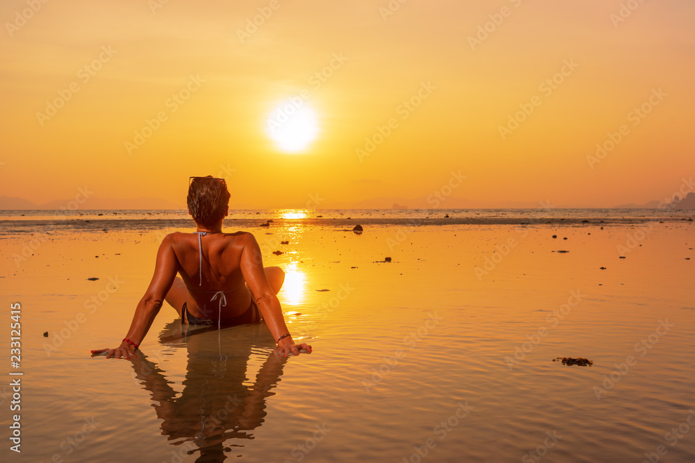 Silhouette of a young and fit woman on the beach at sunset