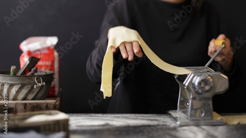 Fresh pasta dough being turned through a pasta machine photo