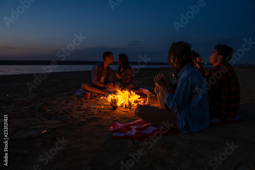 Camp on the beach. Group of young couples having picnic with bonfire