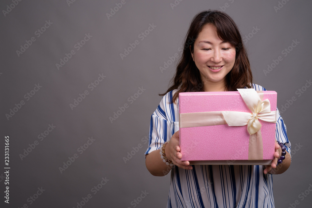 Mature beautiful Asian businesswoman holding gift box Mature beautiful Asian businesswoman holding gift box