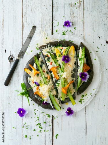 A black pizza with asparagus and chanterelle mushrooms photo