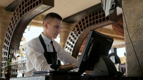 Man or waiter in apron at counter with cashbox working at the restaurant