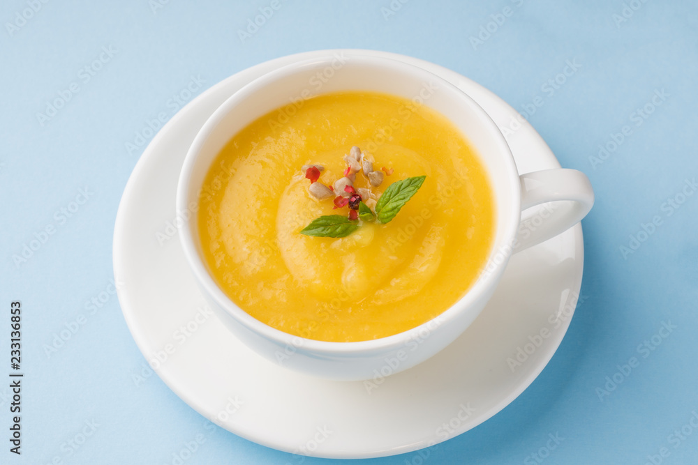 Pumpkin soup mashed with spices in a Cup on a blue background. Pumpkin soup mashed with spices in a Cup on a blue background.