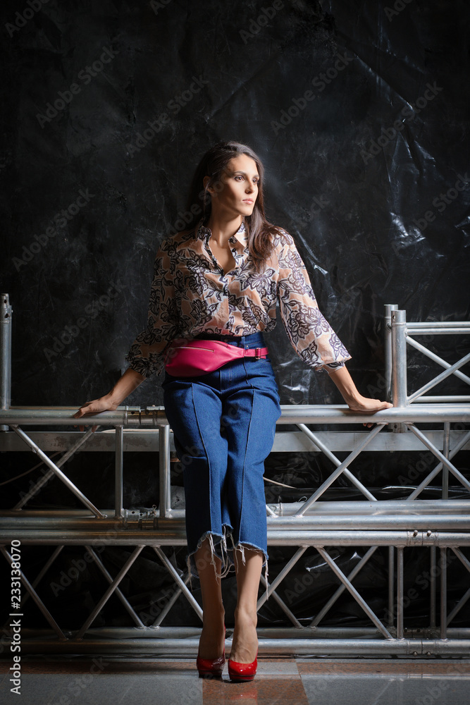 Fototapeta premium Beautiful girl in shirt with flower print, short wide jeans and pink leather waist bag posing