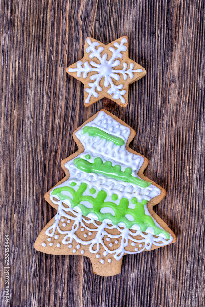 Colorful Christmas gingerbread in the shape of a Christmas tree and in the shape of a star decorated with white and green icing are on a wooden board Colorful Christmas gingerbread in the shape of a Christmas tree and in the shape of a star decorated with white and green icing are on a wooden board