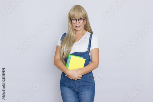 Blond woman in denim overalls with books in her hands