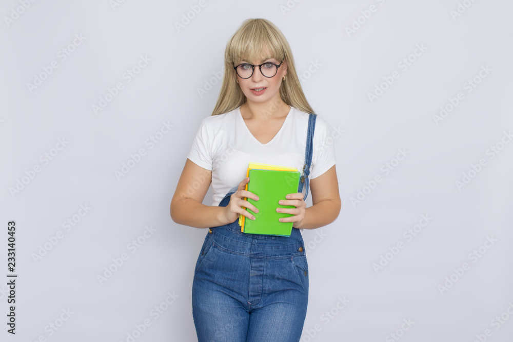 Blond woman in denim overalls with books in her hands Blond woman in denim overalls with books in her hands