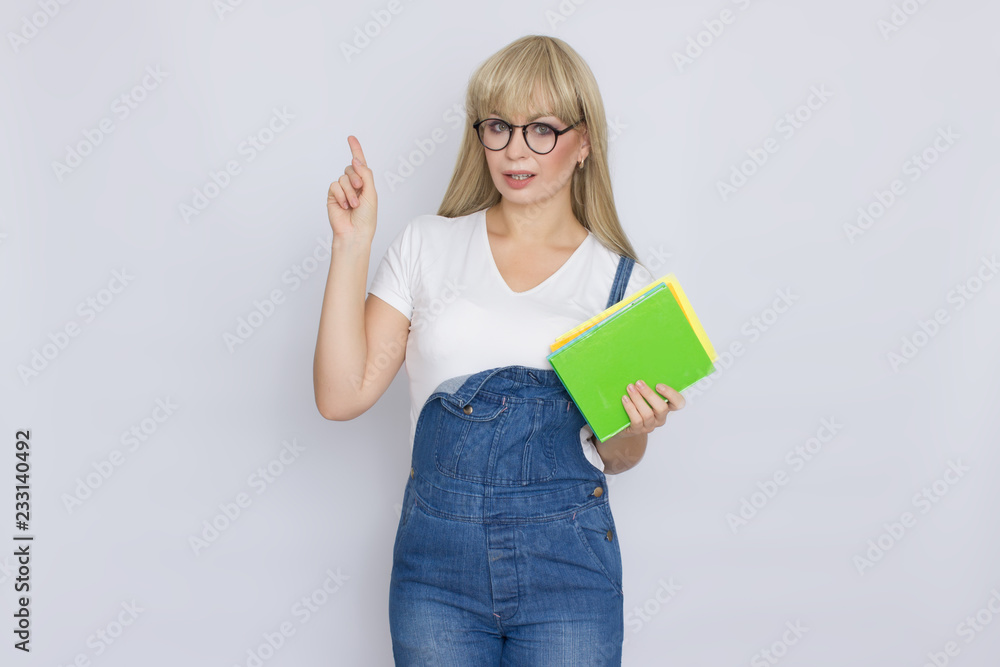 Blond woman in denim overalls with books in her hands Blond woman in denim overalls with books in her hands