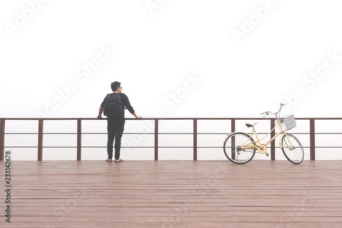 Asian man travelers standing on the balcony with bicycle with dense white fog. The concept of freedom and liberation