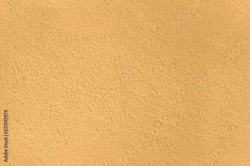 Textured concrete wall  with an orange yellow hue, great as a backgroud texture.