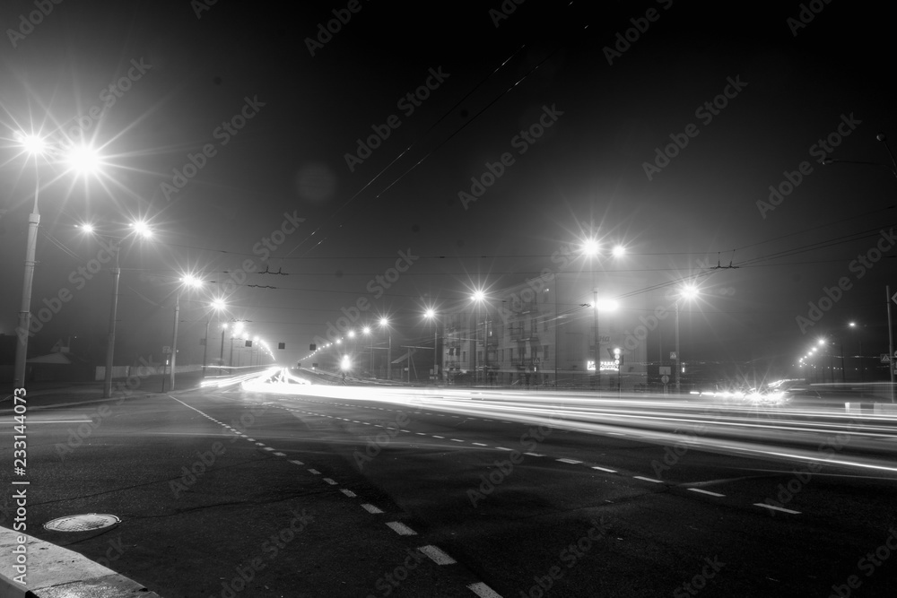 Cars drive at speed through the city at night.