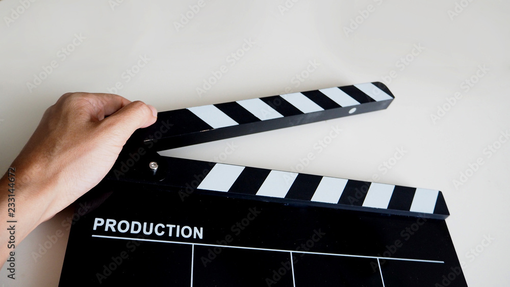 Hand with clapper board or movie slate use in video production or film and cinema industry. It's black color on white background.