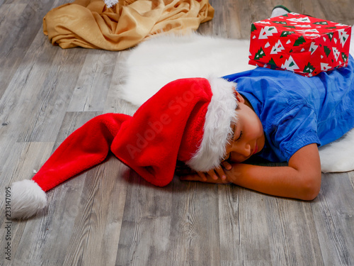 Boy in Christmas hat sleeping on fur rug