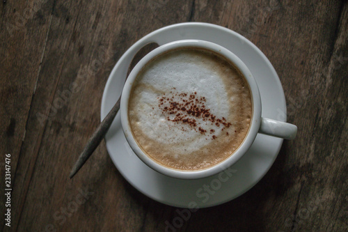 A cup of coffee in the wooden table.