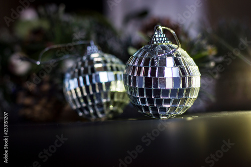 A disco ball like christmas tree toy hanging on a pine tree branch with pine needles.